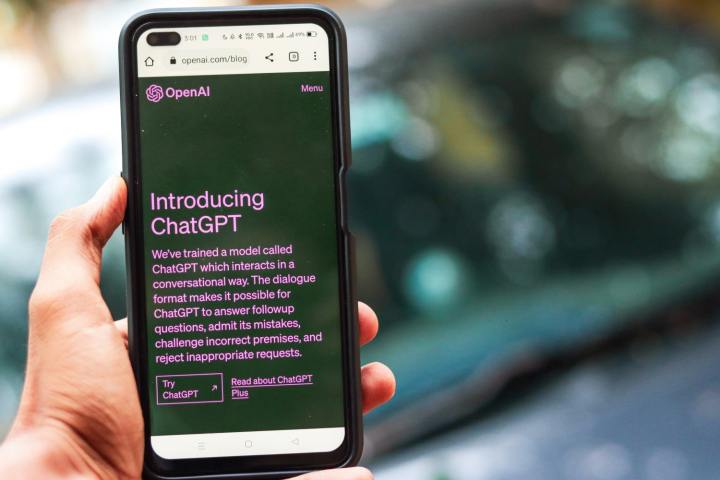 يد شخص تحمل هاتفًا ذكيًا. يعرض الهاتف الذكي موقع الويب الخاص بـ ChatGPT Generator AI.