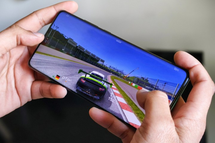 تم حمل هاتف OnePlus 12 بيد الشخص الذي يقوم بتشغيل Real Racing 3.