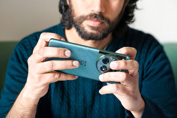 شخص يحمل هاتف OnePlus 12 الأخضر بين يديه أثناء ممارسة الألعاب.