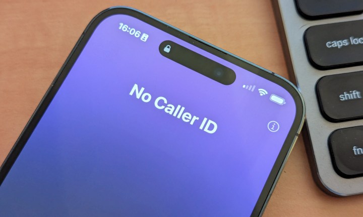 iPhone 14 Pro Max ملقى على مكتب بجوار لوحة المفاتيح مع وجود مكالمة واردة تظهر