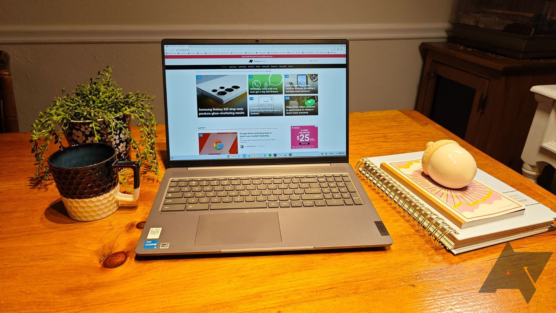 جهاز Lenovo Chromebook مفتوح على طاولة خشبية بجوار دفاتر الملاحظات والكوب